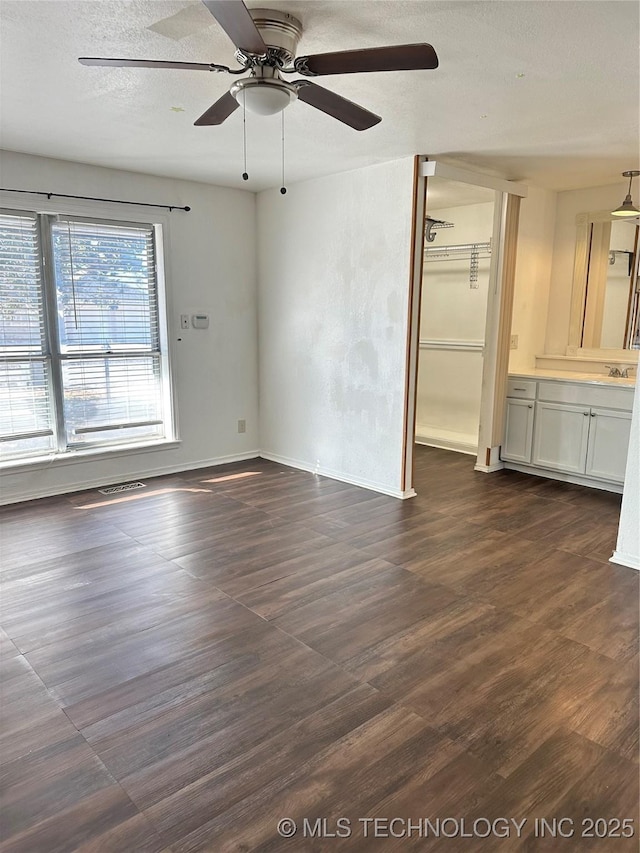 empty room with ceiling fan, dark hardwood / wood-style floors, sink, and a textured ceiling