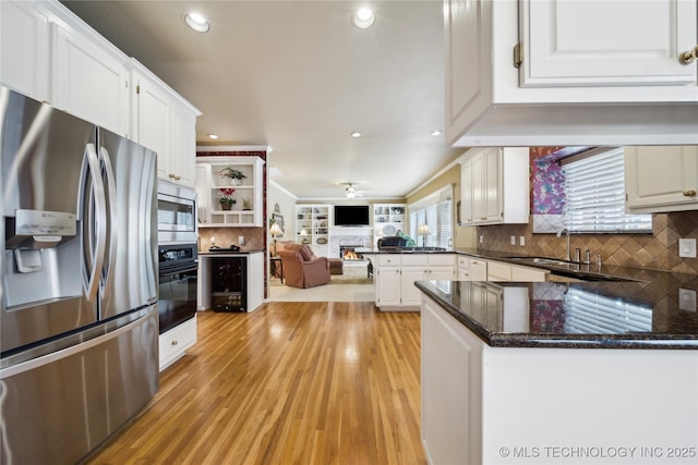 kitchen with appliances with stainless steel finishes, tasteful backsplash, white cabinetry, sink, and kitchen peninsula