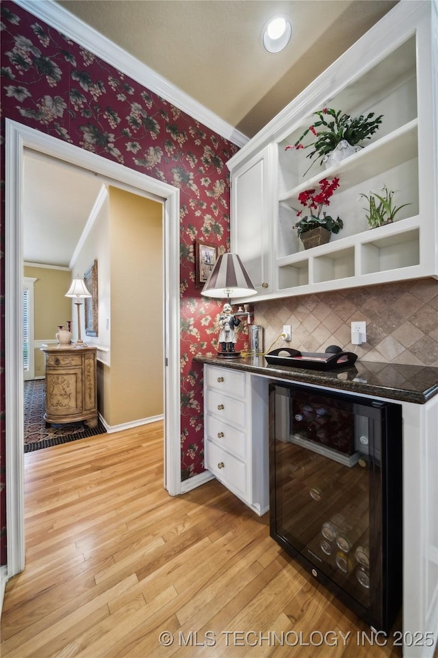 bar featuring white cabinetry, ornamental molding, beverage cooler, and light wood-type flooring