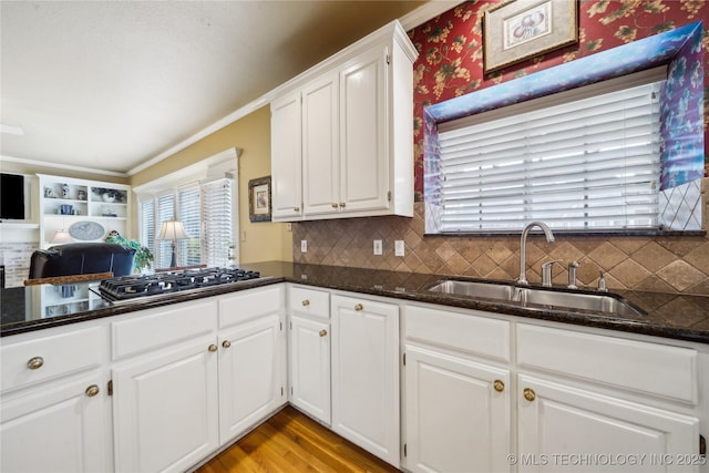 kitchen with white cabinetry, stainless steel gas cooktop, dark stone counters, and sink