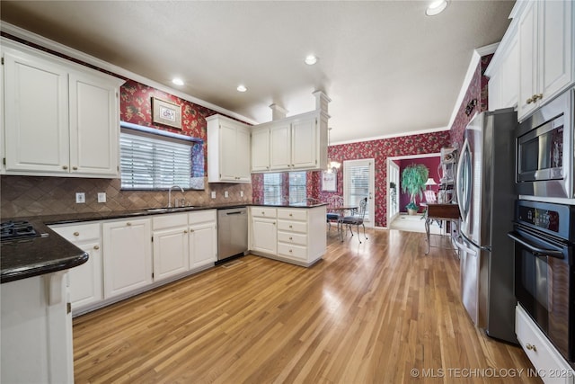 kitchen with white cabinetry, stainless steel appliances, crown molding, and sink