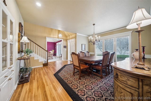 dining room featuring ornamental molding, a chandelier, and light wood-type flooring