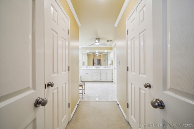 corridor with crown molding and light carpet