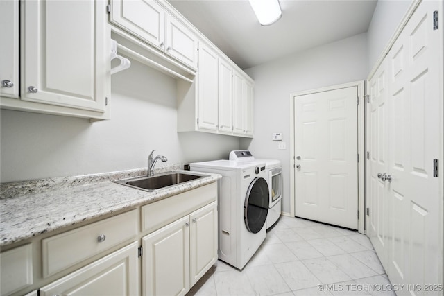 clothes washing area with cabinets, separate washer and dryer, and sink