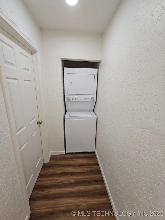 clothes washing area featuring stacked washer / drying machine and dark wood-type flooring