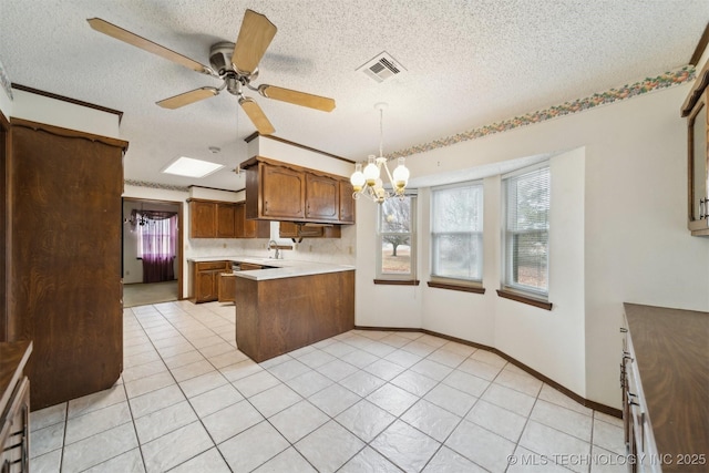 kitchen with hanging light fixtures, kitchen peninsula, a textured ceiling, and light tile patterned flooring