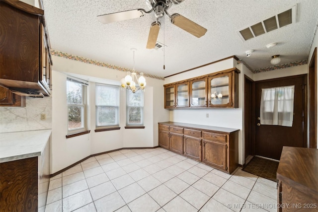 kitchen featuring light tile patterned floors, decorative light fixtures, ceiling fan with notable chandelier, and a textured ceiling