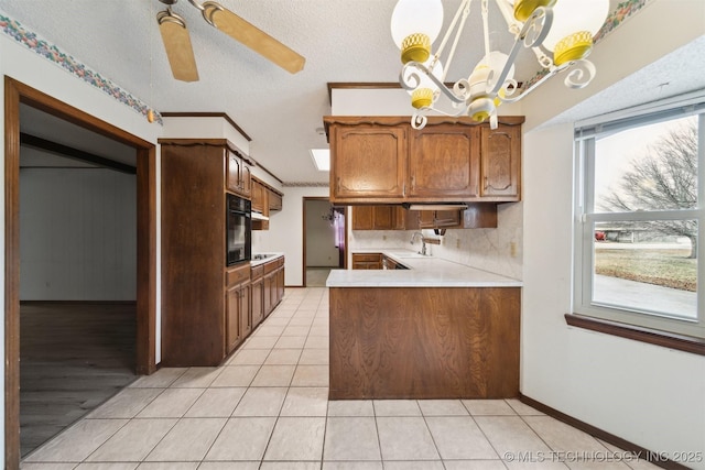 kitchen featuring sink, hanging light fixtures, light tile patterned floors, black appliances, and a textured ceiling