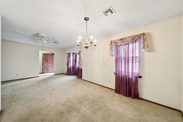 empty room with ceiling fan with notable chandelier, light colored carpet, and a textured ceiling