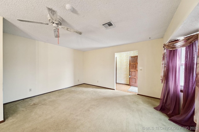 empty room featuring light carpet, ceiling fan, and a textured ceiling