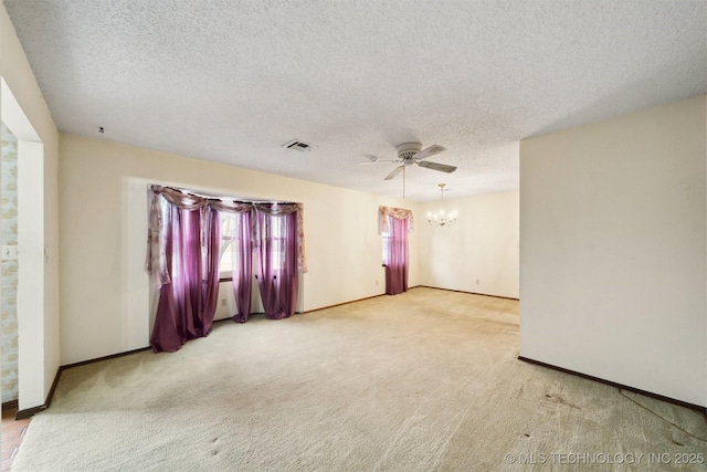 carpeted spare room with ceiling fan with notable chandelier and a textured ceiling