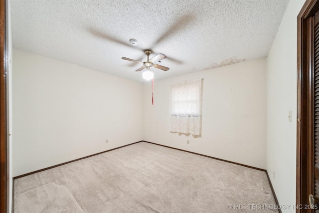 carpeted empty room featuring ceiling fan and a textured ceiling