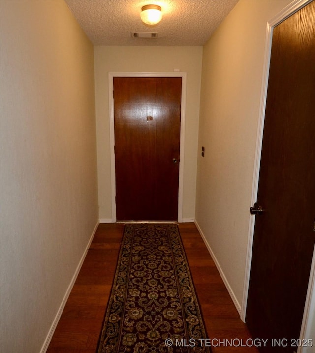 hall with dark wood-type flooring and a textured ceiling