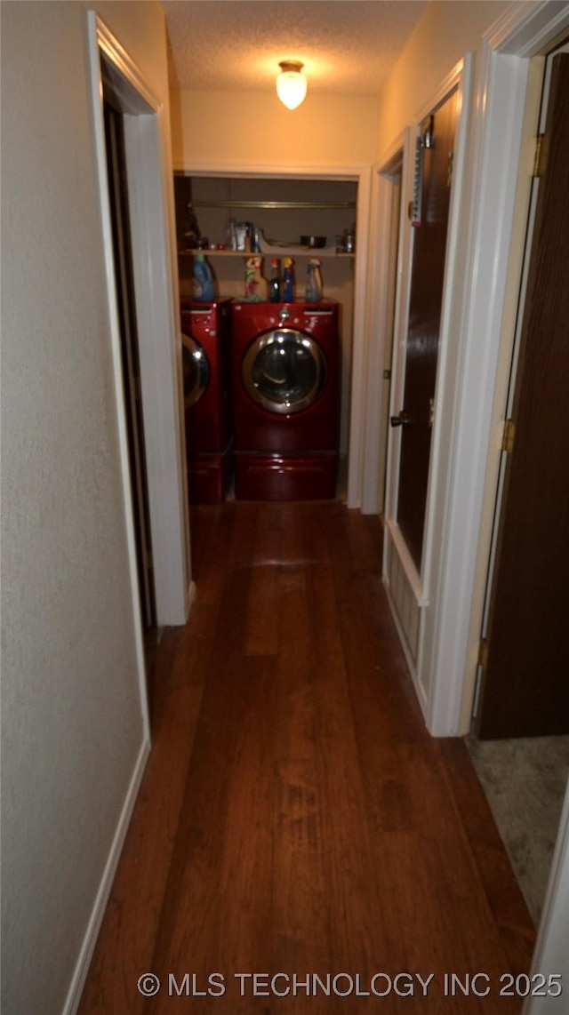 corridor with a textured ceiling, dark wood-type flooring, and washing machine and clothes dryer