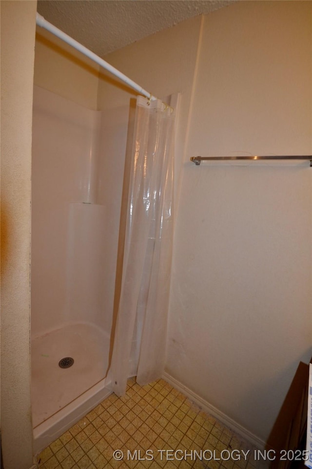 bathroom with curtained shower and a textured ceiling