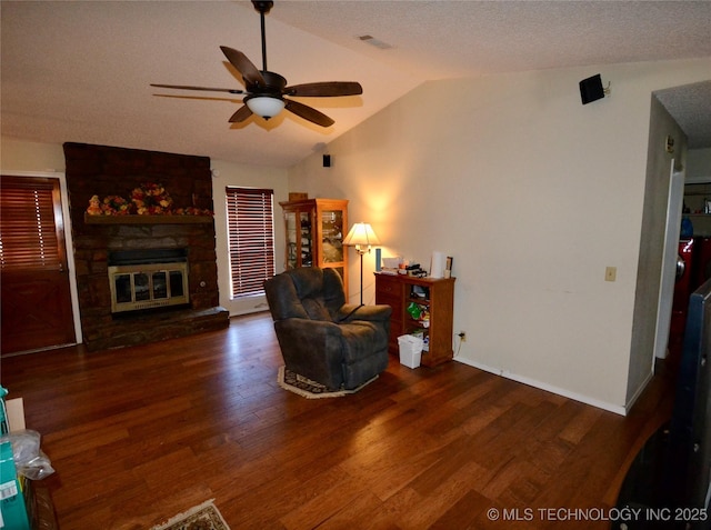 living room with a fireplace, lofted ceiling, ceiling fan, dark wood-type flooring, and a textured ceiling