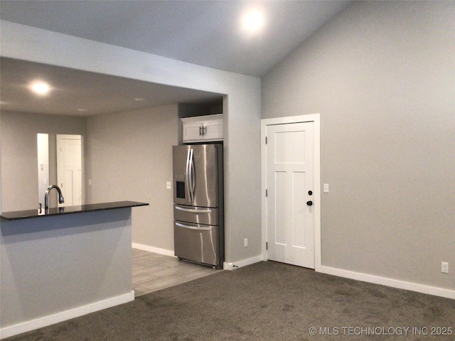 kitchen with stainless steel refrigerator with ice dispenser, sink, dark colored carpet, white cabinetry, and kitchen peninsula