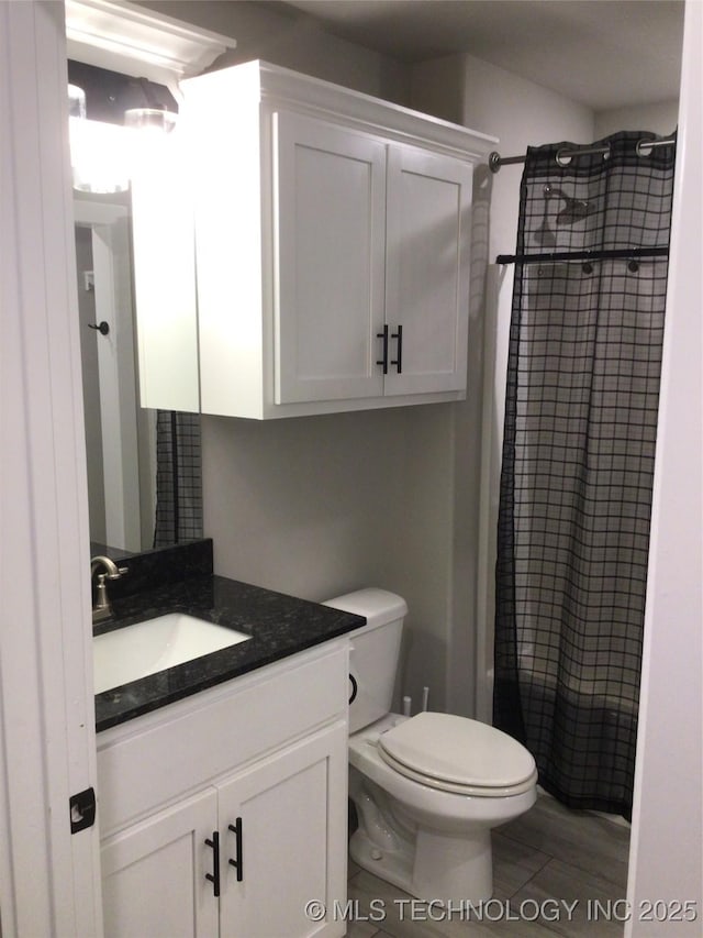 bathroom featuring hardwood / wood-style flooring, vanity, curtained shower, and toilet