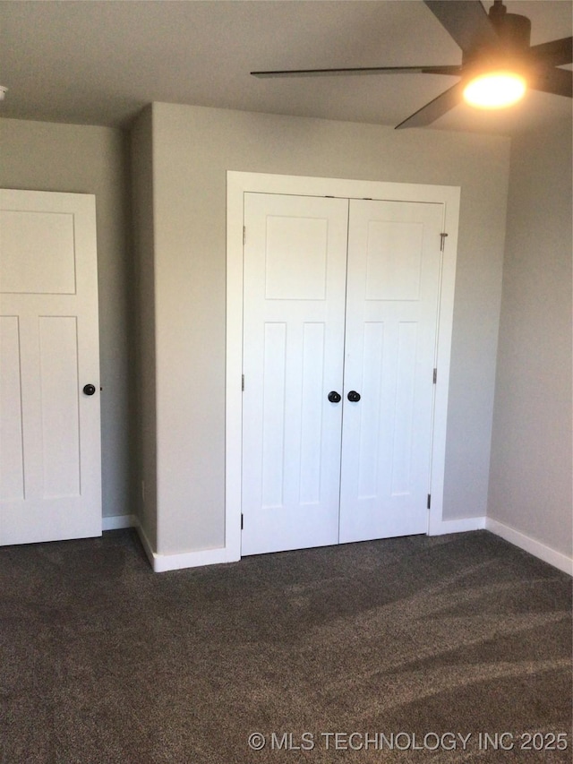 unfurnished bedroom featuring ceiling fan, dark carpet, and a closet