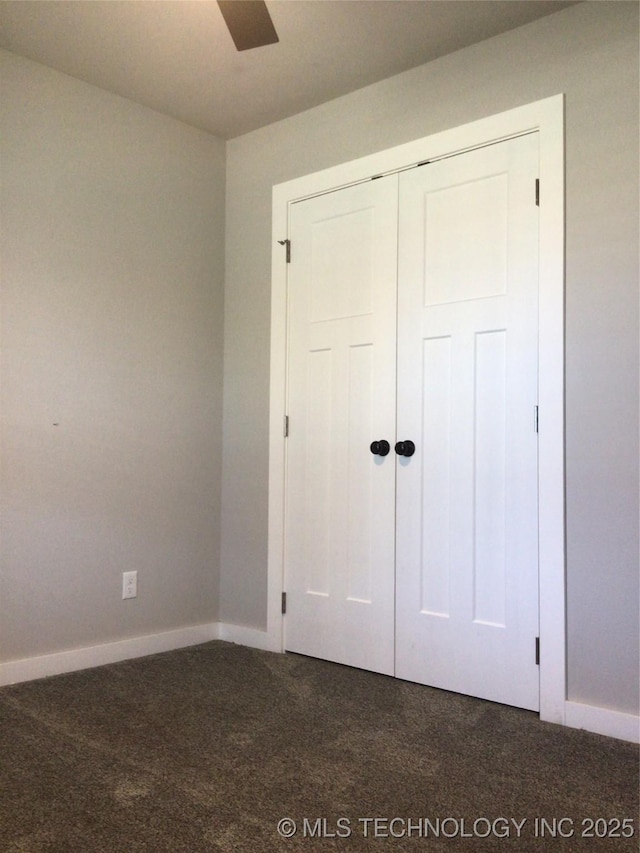 unfurnished bedroom featuring dark carpet and a closet