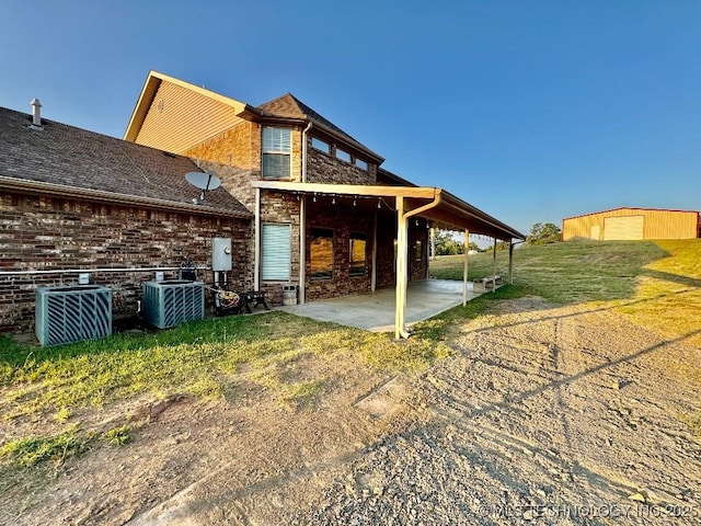 back of house featuring a lawn, a patio, and central air condition unit