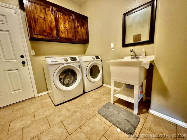 clothes washing area featuring cabinets, light tile patterned floors, and washer and clothes dryer