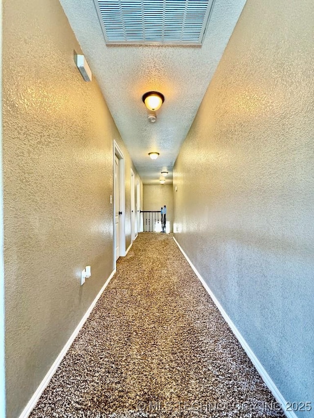 hallway with a textured ceiling and carpet