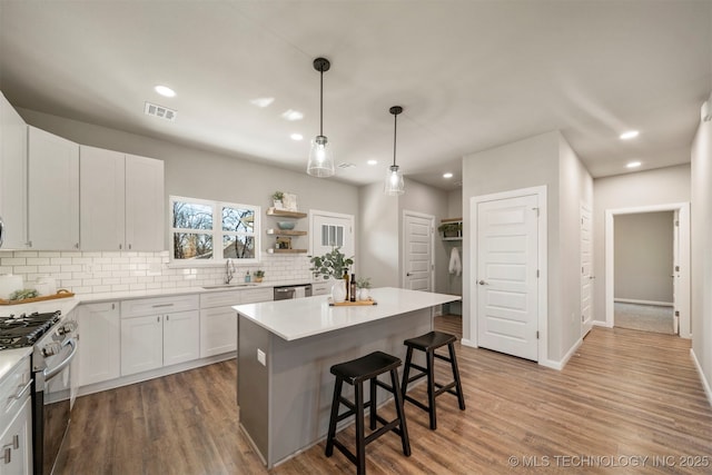 kitchen featuring sink, a breakfast bar area, appliances with stainless steel finishes, white cabinetry, and a center island