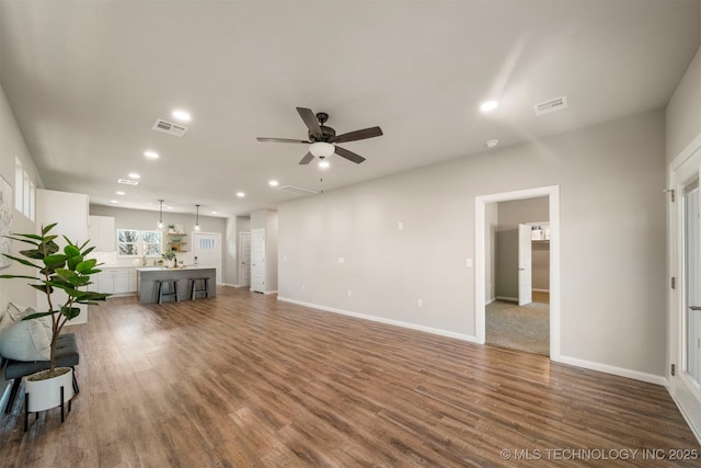 unfurnished living room featuring ceiling fan and dark hardwood / wood-style flooring