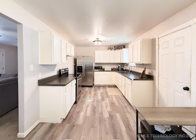 kitchen featuring white cabinetry, sink, light hardwood / wood-style floors, and appliances with stainless steel finishes