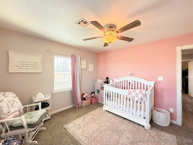 bedroom with a crib, ceiling fan, and carpet