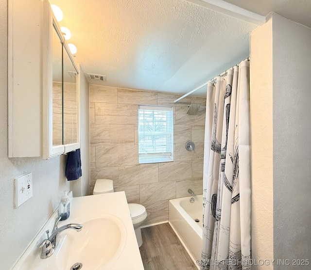 full bathroom featuring sink, hardwood / wood-style flooring, toilet, shower / bath combo, and a textured ceiling