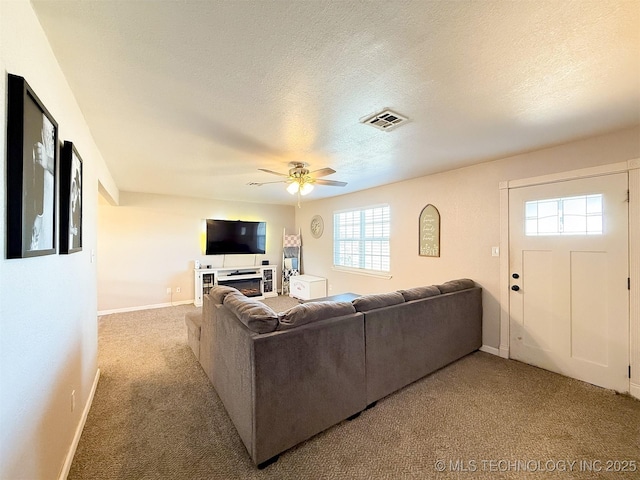 living room featuring ceiling fan, light colored carpet, and a textured ceiling