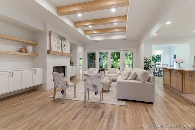 living room featuring a fireplace, light hardwood / wood-style floors, and beamed ceiling