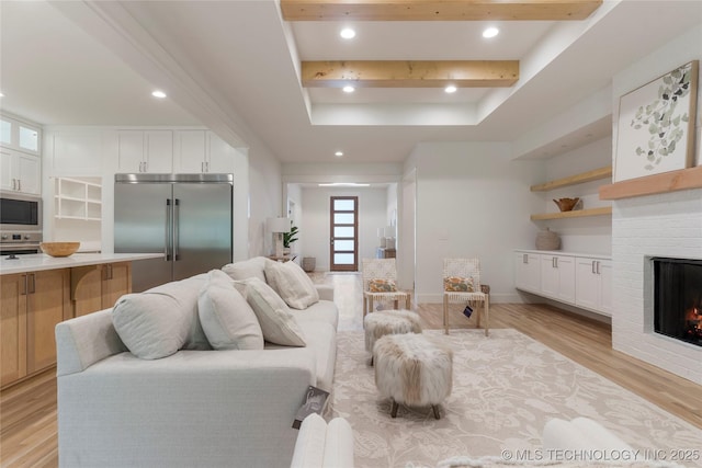 living room featuring a raised ceiling, a fireplace, and light hardwood / wood-style flooring