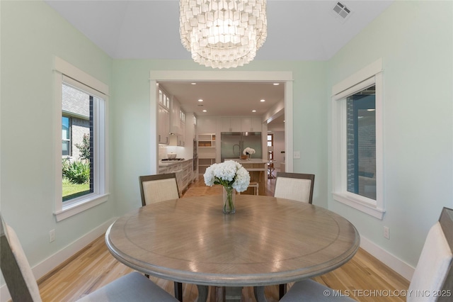 dining space featuring an inviting chandelier and light wood-type flooring