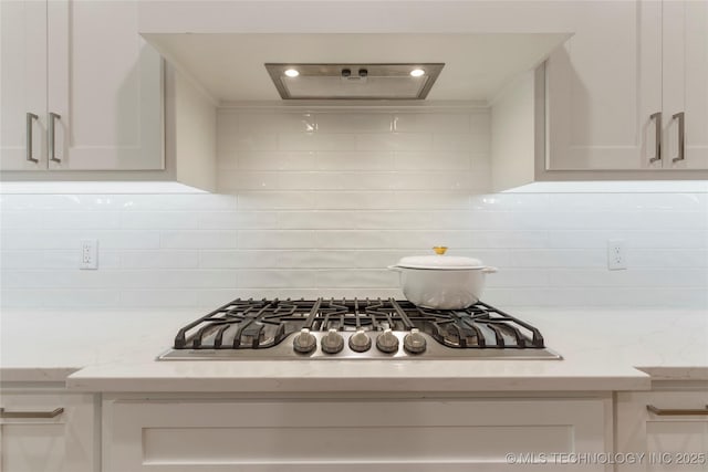 details featuring light stone counters, white cabinetry, and stainless steel gas stovetop