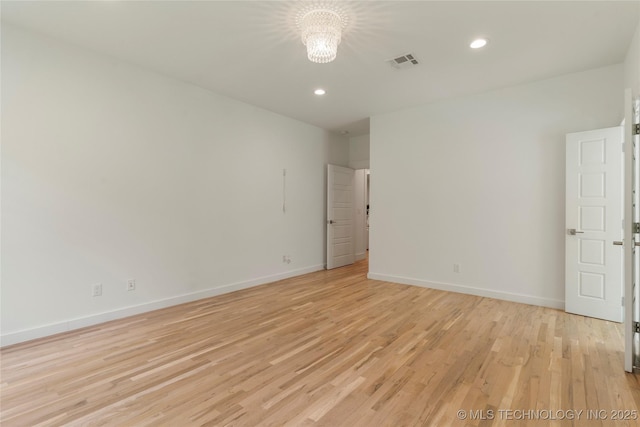 empty room with an inviting chandelier and light hardwood / wood-style flooring