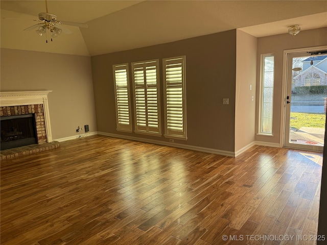 unfurnished living room featuring hardwood / wood-style flooring, ceiling fan, vaulted ceiling, and a fireplace