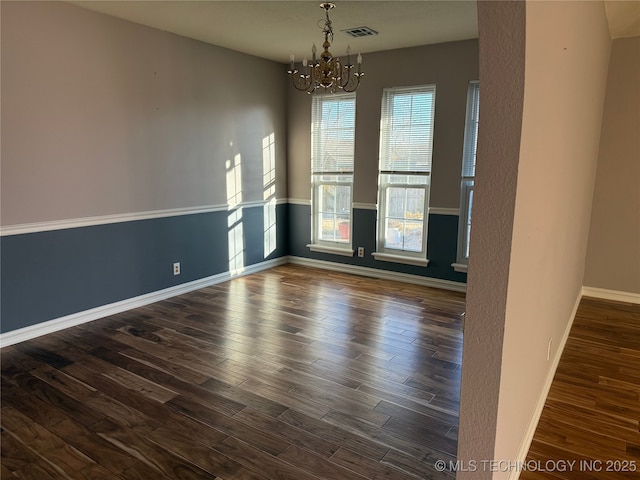 spare room with an inviting chandelier and dark hardwood / wood-style floors