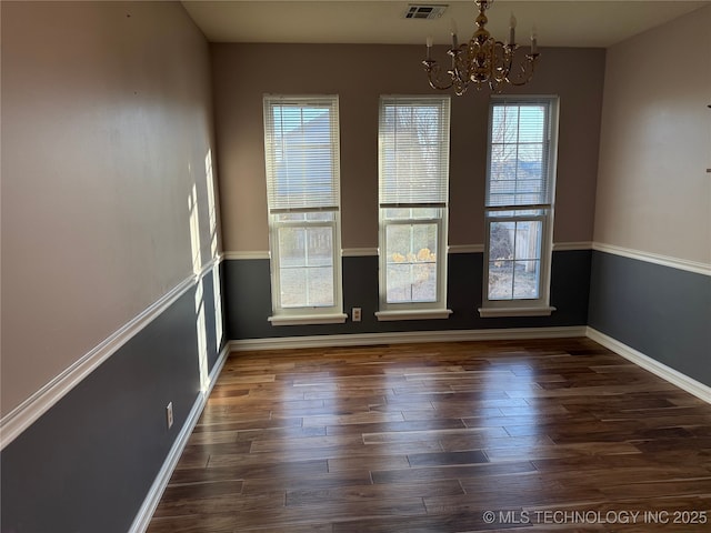 unfurnished dining area featuring dark hardwood / wood-style floors and a chandelier