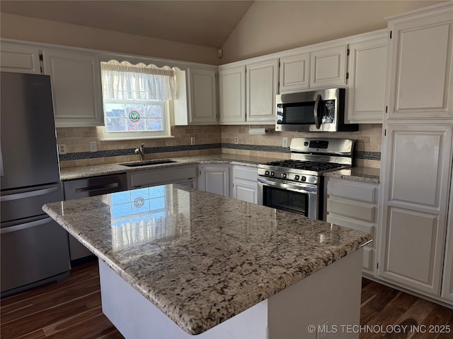 kitchen featuring sink, white cabinetry, appliances with stainless steel finishes, a kitchen island, and light stone countertops