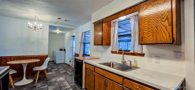 kitchen featuring sink, a chandelier, independent washer and dryer, and decorative light fixtures