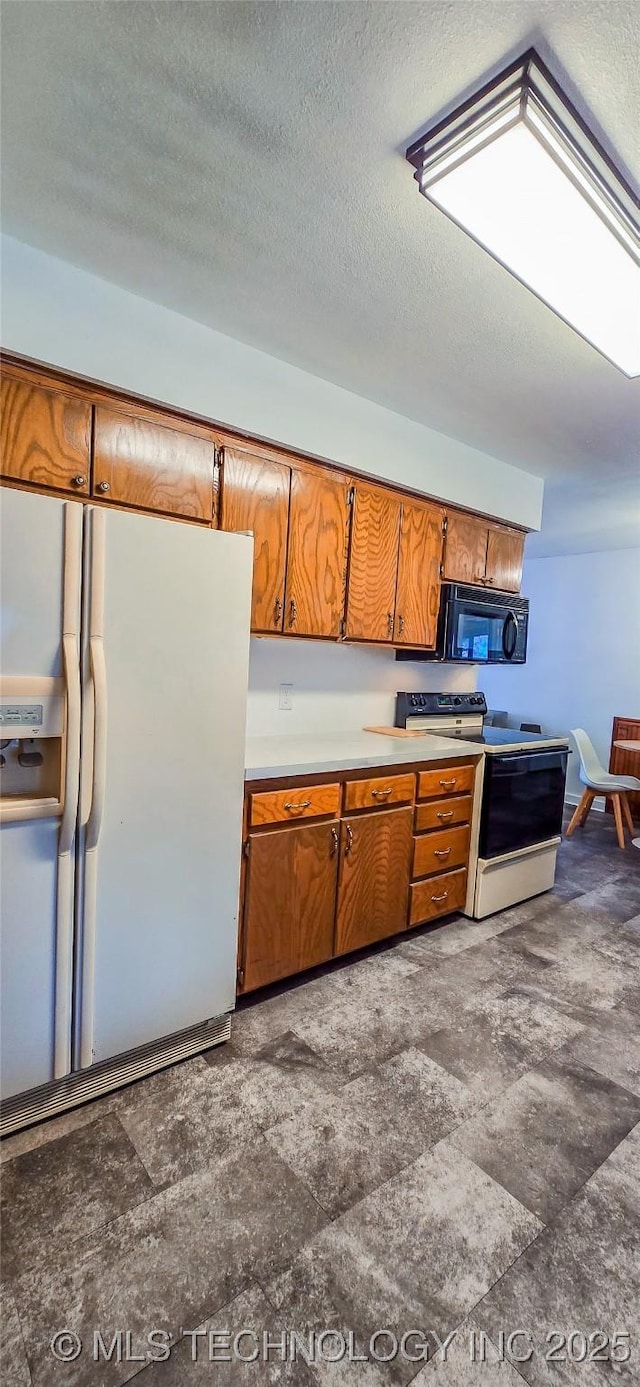 kitchen featuring electric stove, white refrigerator with ice dispenser, and a textured ceiling