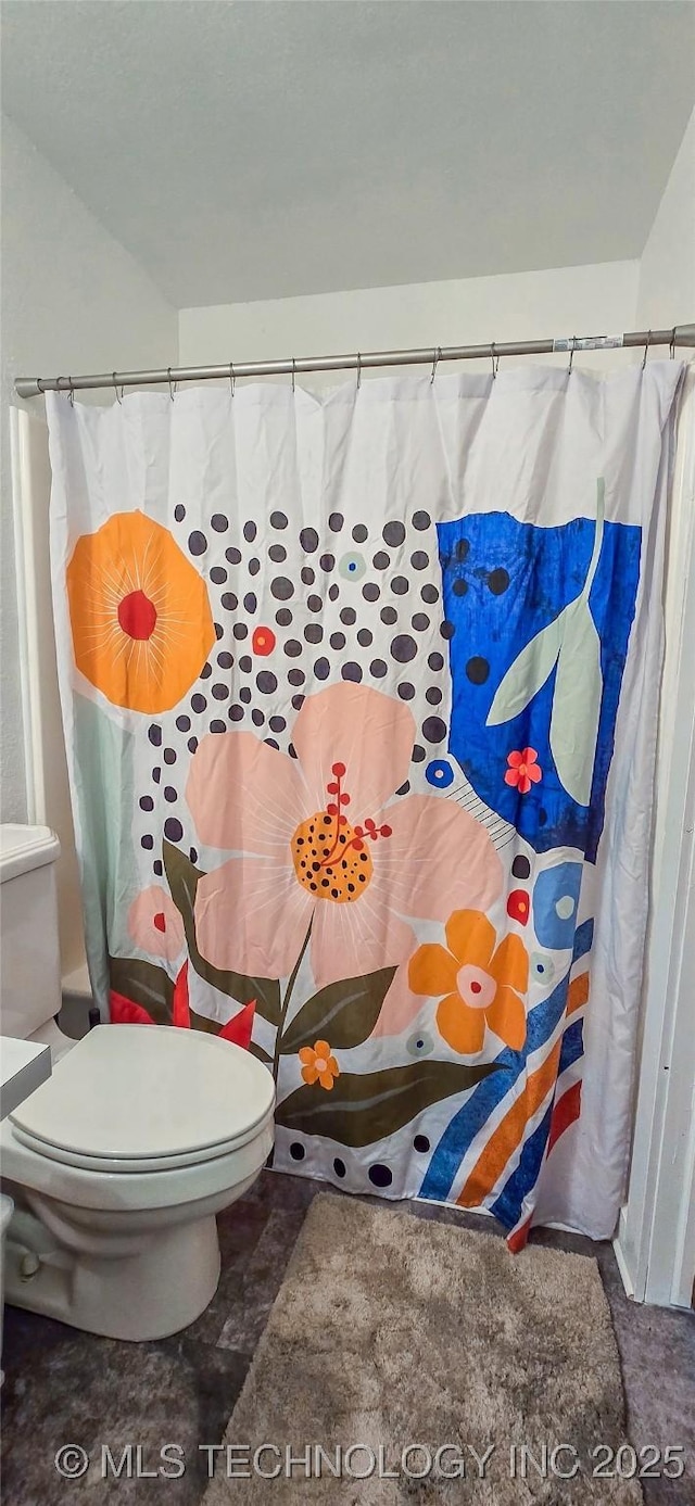 bathroom featuring a shower with curtain and toilet