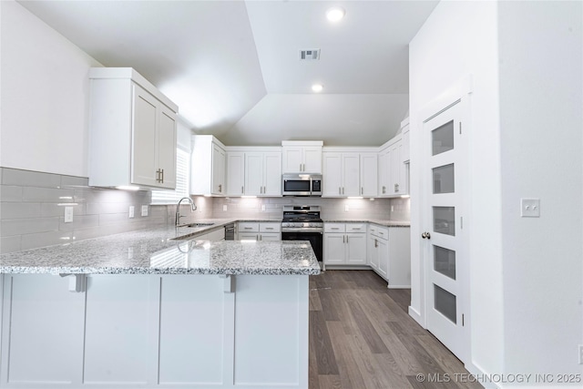 kitchen with a breakfast bar, sink, appliances with stainless steel finishes, kitchen peninsula, and white cabinets