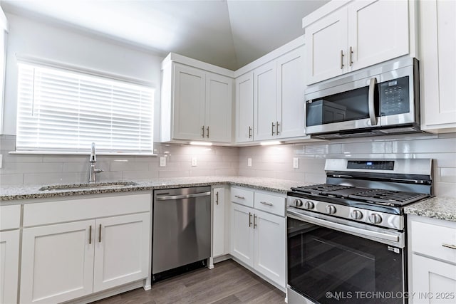 kitchen featuring stainless steel appliances, sink, white cabinets, and light stone counters