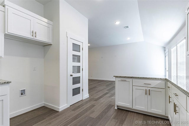 kitchen with light stone counters, lofted ceiling, and white cabinets