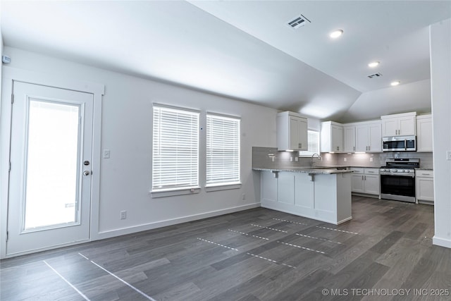 kitchen featuring tasteful backsplash, sink, white cabinets, kitchen peninsula, and stainless steel appliances