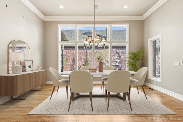 dining space featuring crown molding, light wood-type flooring, and a chandelier